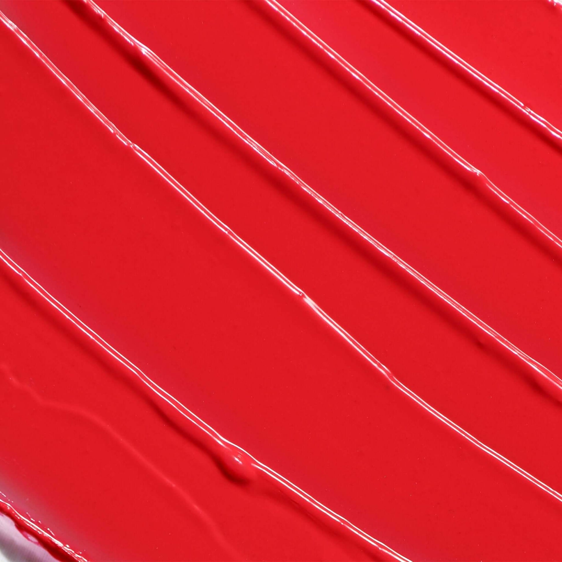 Close-up texture of the Candy Paint Cheek + Lip Tint in a vibrant candy apple red shade, showing the creamy and dewy finish of the product.